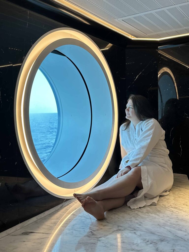 A young lady looking out of a window on virgin voyages